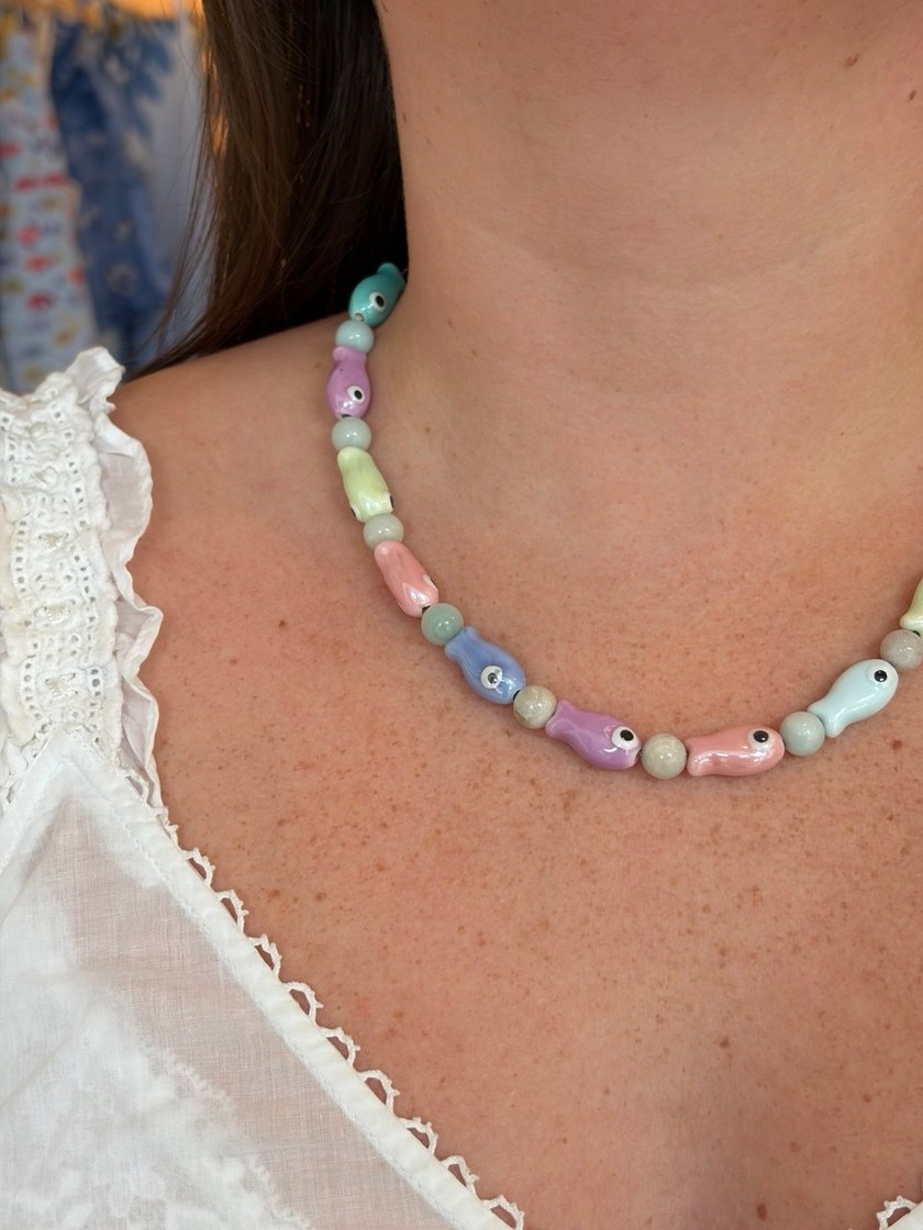 Pastel porcelain fish necklace worn at collarbone length, mint, lilac, butter and pink fish between pale stone rounds.